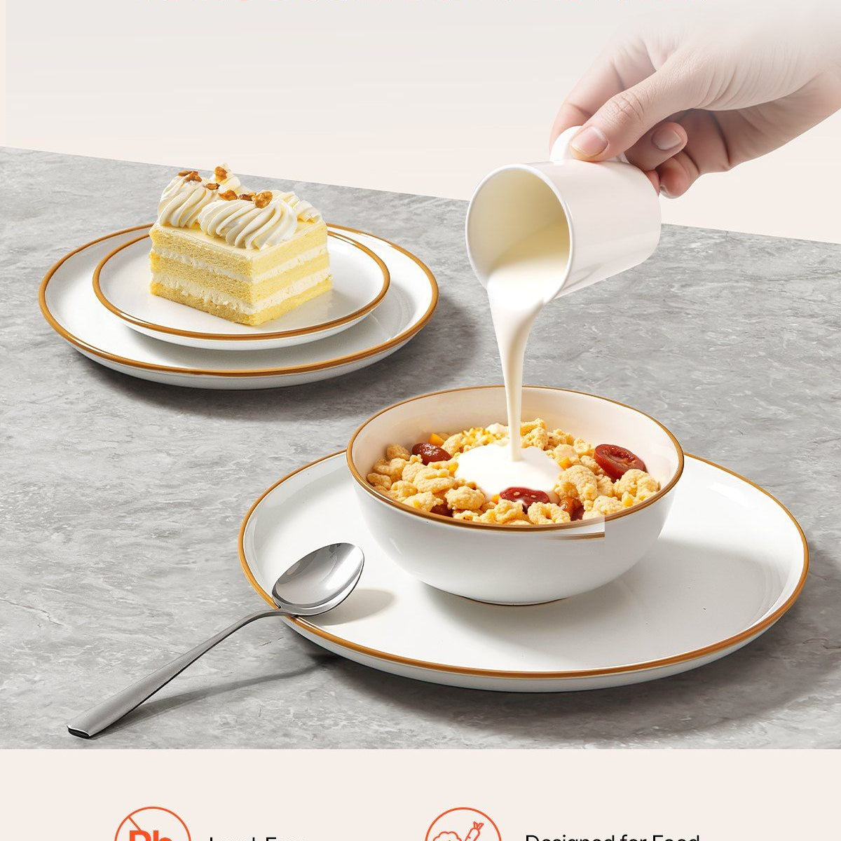 Person pouring milk into a bowl of cereal with a cake on a side plate, on a gray surface.