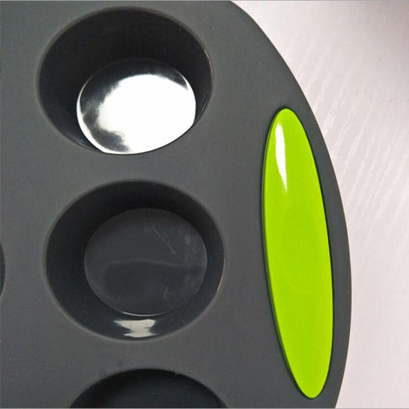 Gray silicone baking mold with three circular cavities and a green handle on a white background