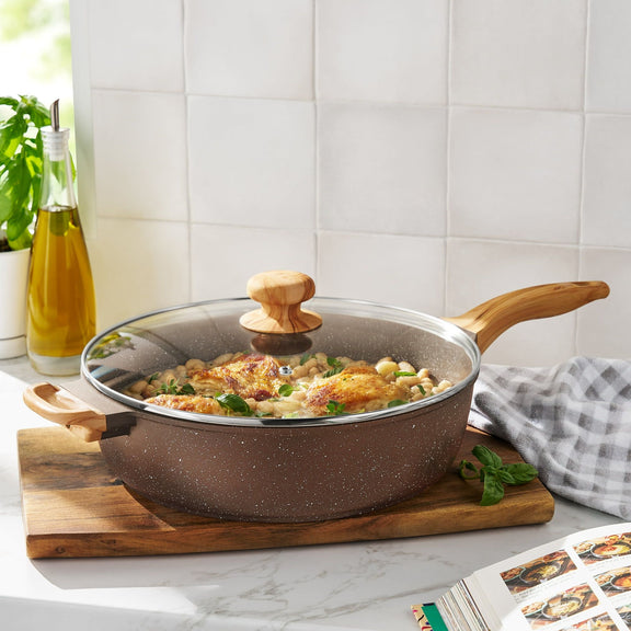 Cooking pan with lid on a wooden cutting board in a kitchen setting