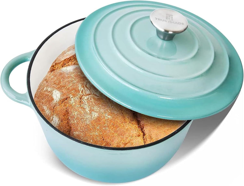 Turquoise enameled cast iron Dutch oven with a lid containing bread on a white background
