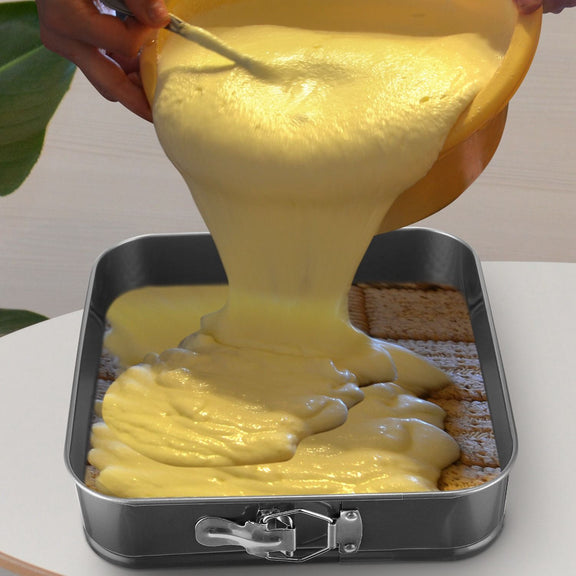 Yellow batter being poured into a metal baking dish.
