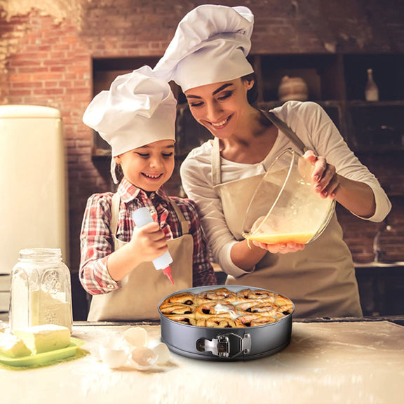 Woman and child in chef hats and aprons preparing food in a kitchen.
