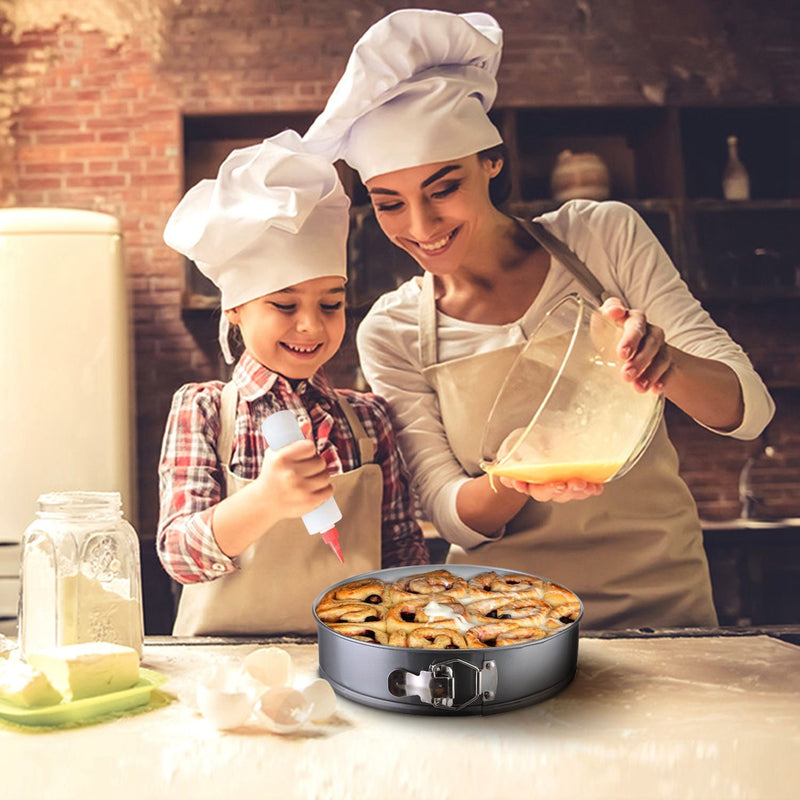 Woman and child in chef hats and aprons preparing food in a kitchen.