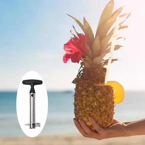 Pineapple with a drink and a hand holding a pineapple corer against a beach background