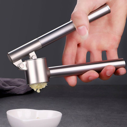 Hand using a garlic press with crushed garlic on a dark background
