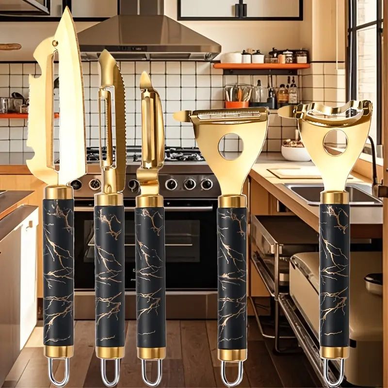 Set of gold-handled kitchen utensils with black marble patterns in a kitchen setting