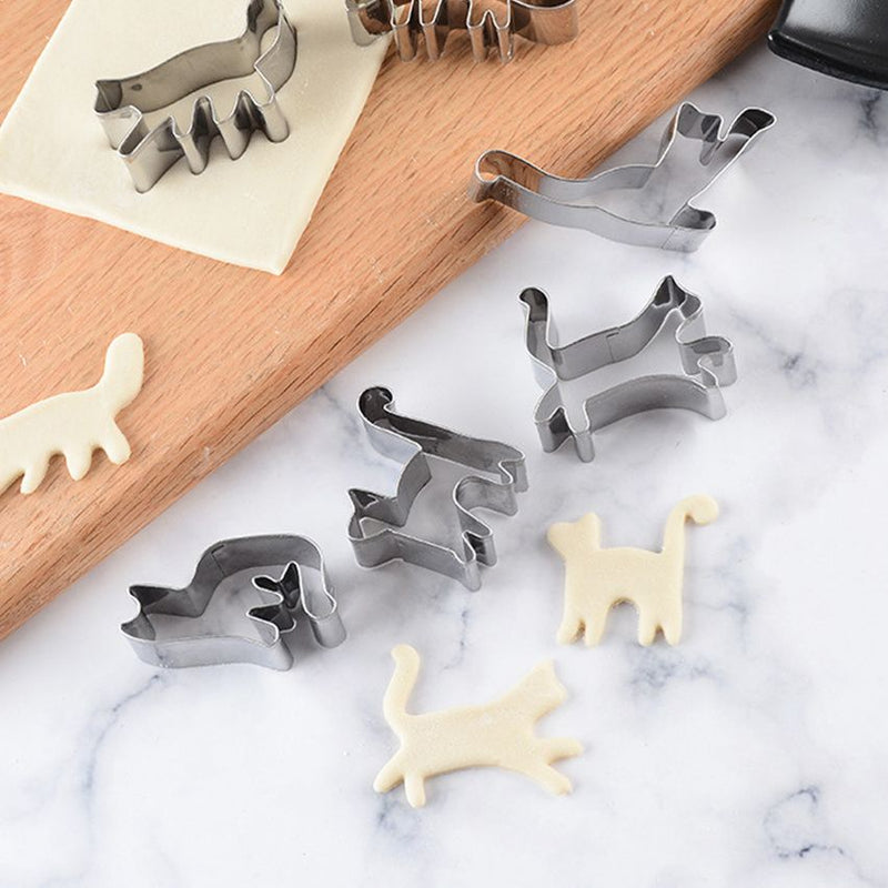 Set of animal-shaped cookie cutters on a marble surface with shaped cookies.