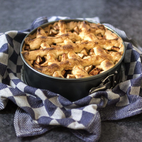 Apple pie in a metal pie dish on a checkered cloth