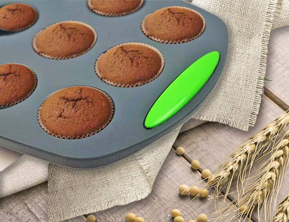 Muffin tray with baked muffins on a wooden surface with wheat stalks.