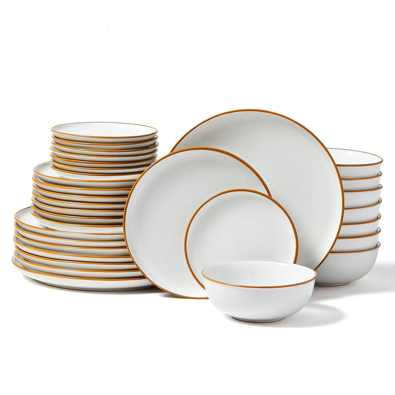 Set of white dinnerware with gold rims on a white background