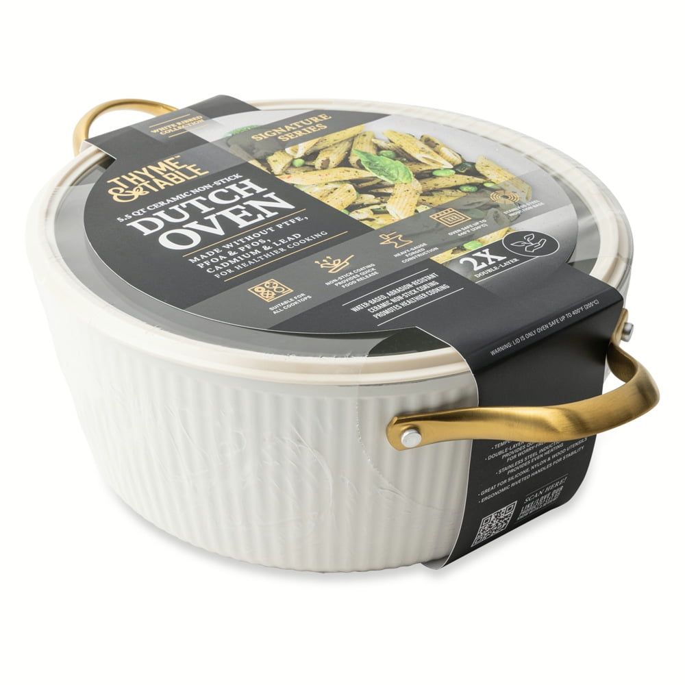 White Dutch oven with gold handles in packaging on a white background