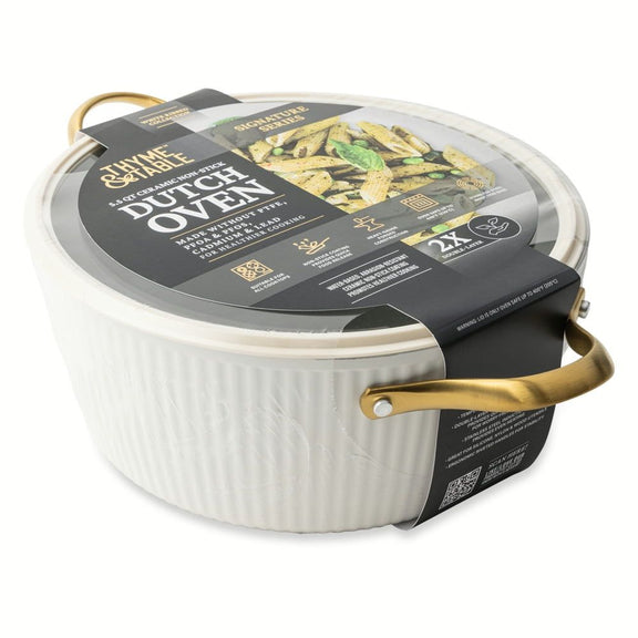 White Dutch oven with gold handles in packaging on a white background