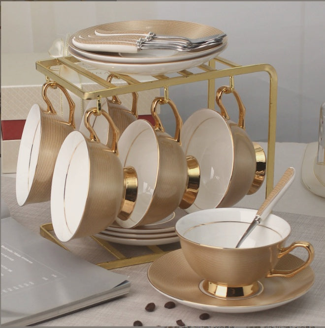 Set of gold and white ceramic tea cups and saucers on a stand with a blurred background.