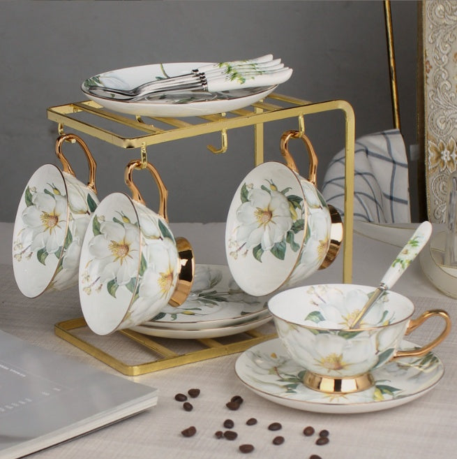 Ceramic tea set with floral design on a gold stand against a neutral background
