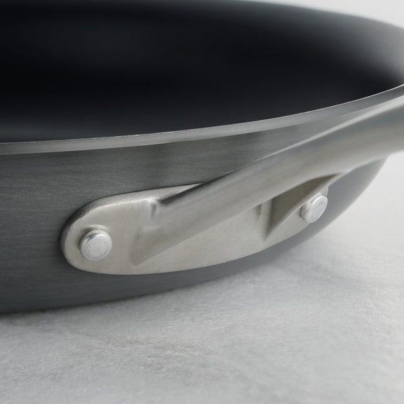 Close-up of a frying pan handle on a light gray background