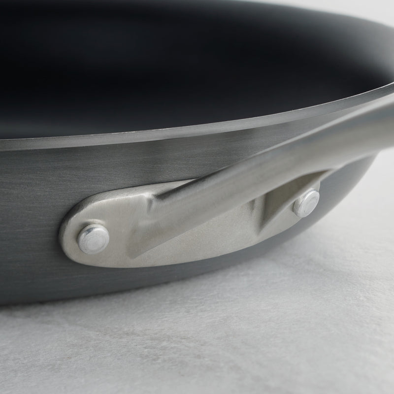 Close-up of a frying pan handle on a light gray background