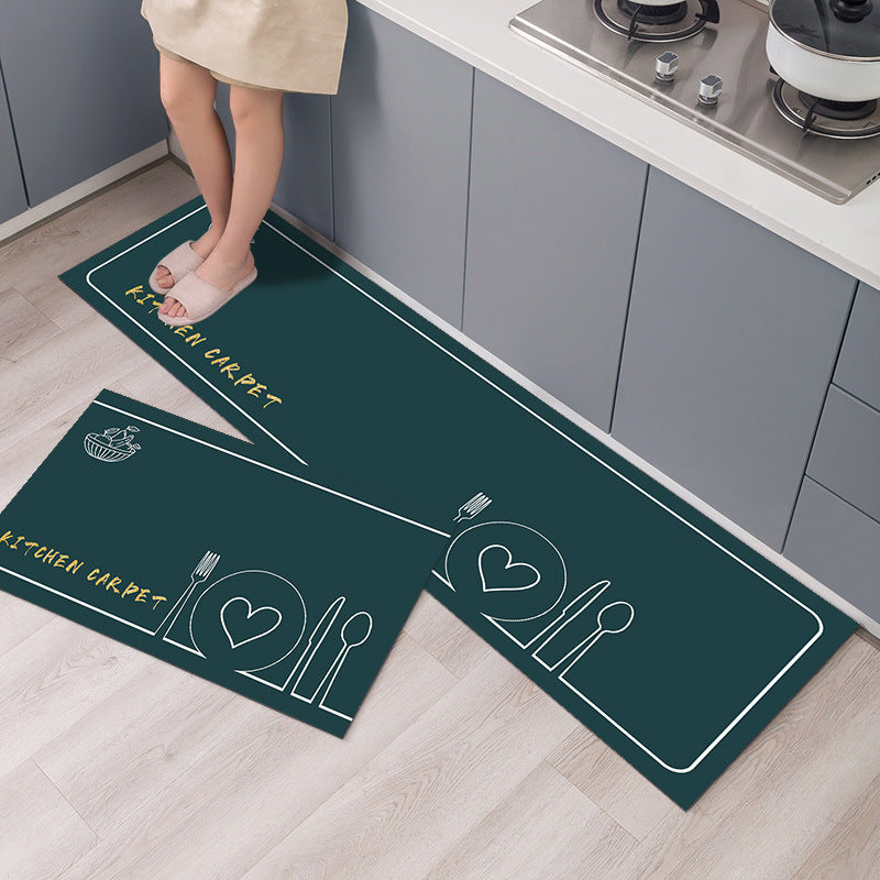 Green kitchen mat with white designs on a wooden floor.