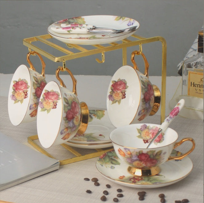 Set of floral teacups and saucers with a gold stand on a table.