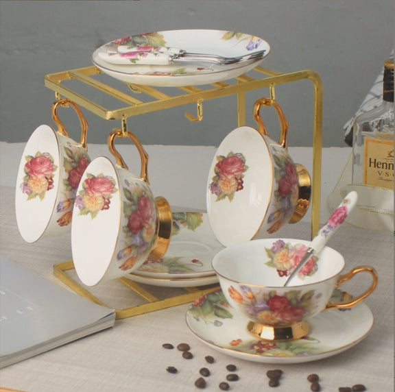 Set of floral teacups and saucers with a gold stand on a table.