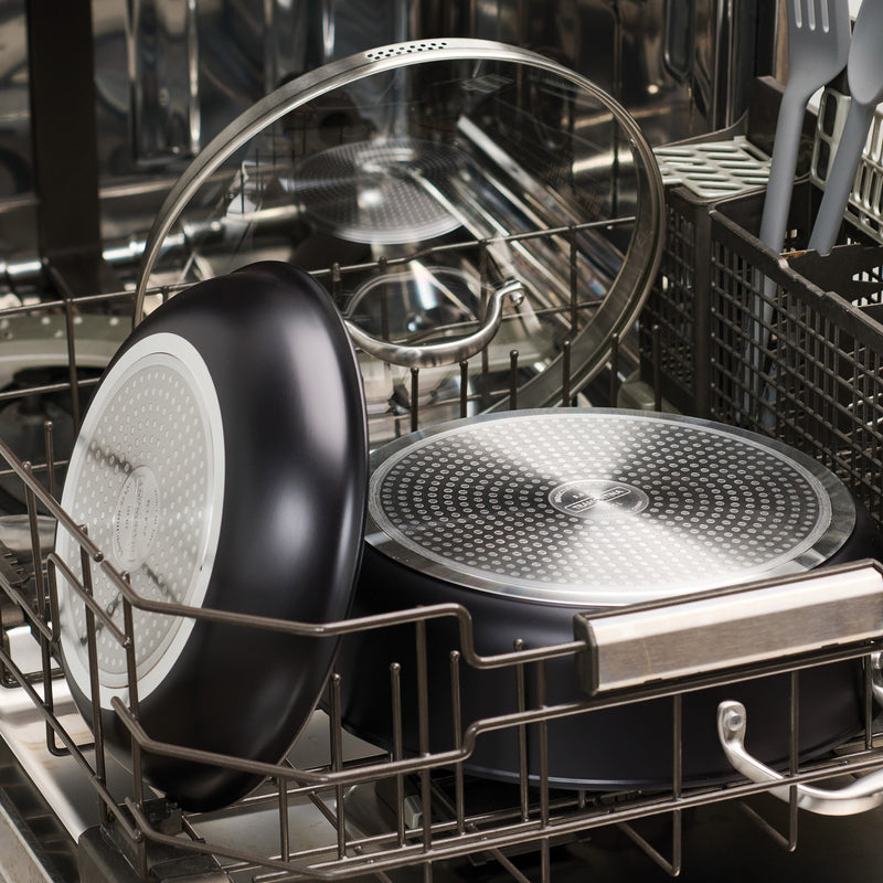 Dishwasher with dishes inside, including a black frying pan and glass bowl.