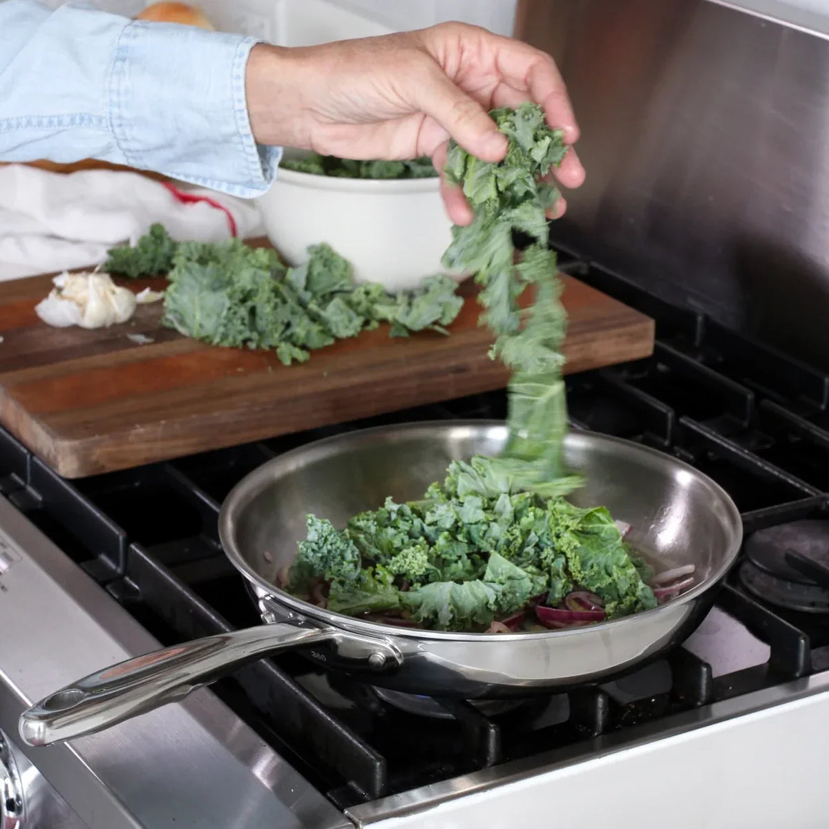 Person throwing vegetables into a frying pan on a stove