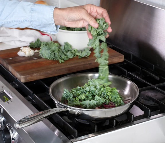 Person throwing vegetables into a frying pan on a stove