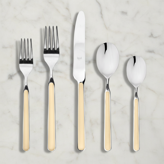 Exactly five cream-handle flatware pieces on a pale marble surface