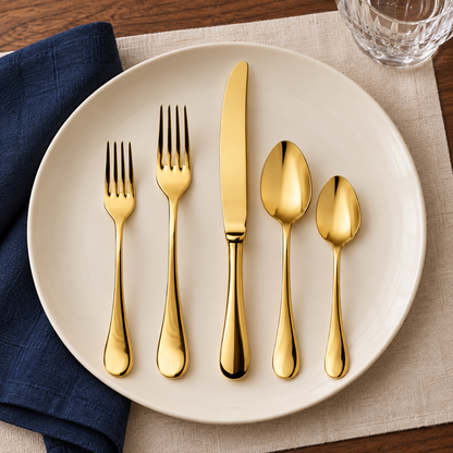 Mepra Brescia Oro polished gold five-piece flatware on ivory plate with navy linen