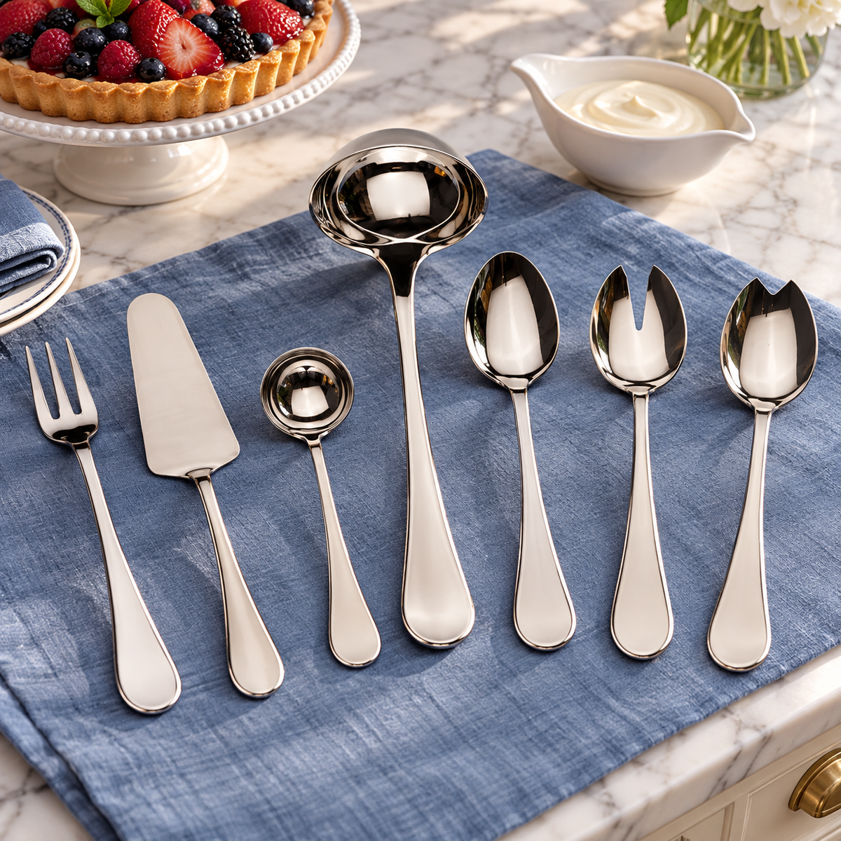 Mepra Brescia seven silver serving tools beside berry tart on blue linen