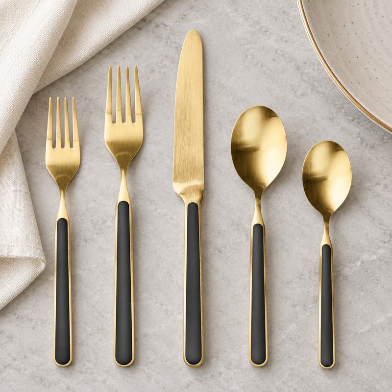 Mepra Fantasia Ice Oro Black five-piece satin gold flatware on pale stone