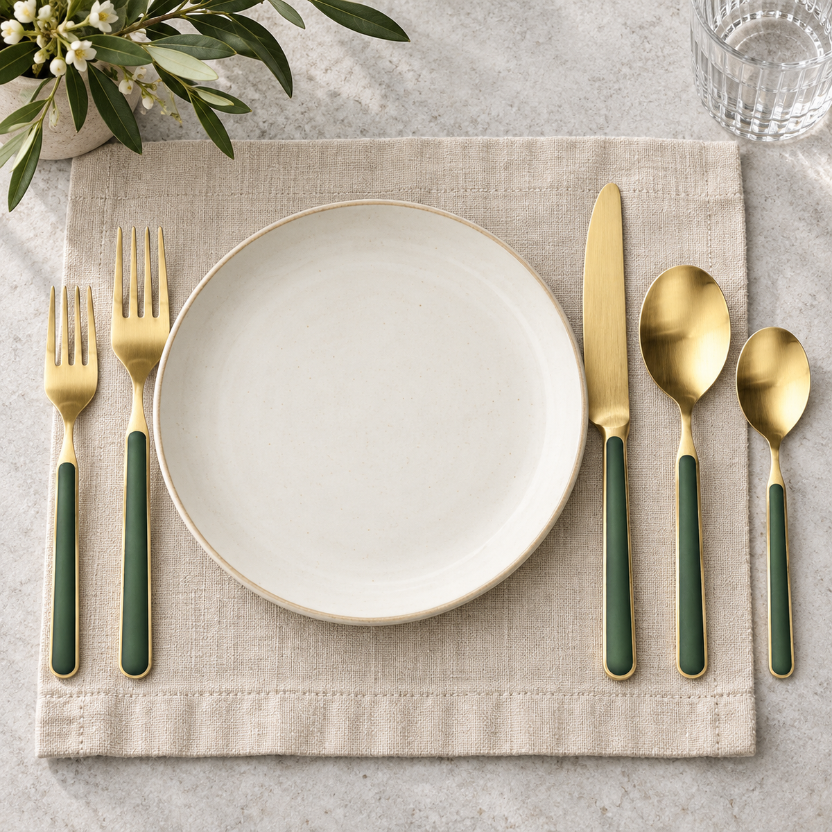 Mepra Fantasia Ice Oro Forest Green five-piece gold flatware beside an ivory plate