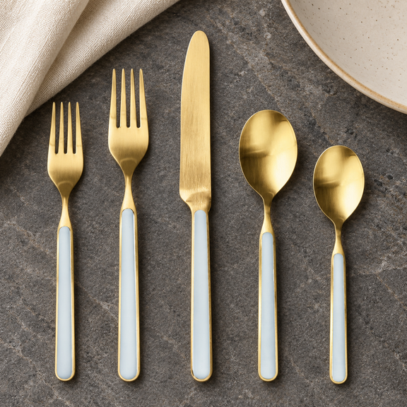 Mepra Fantasia Ice Oro Light Blue five-piece satin gold flatware on dark stone