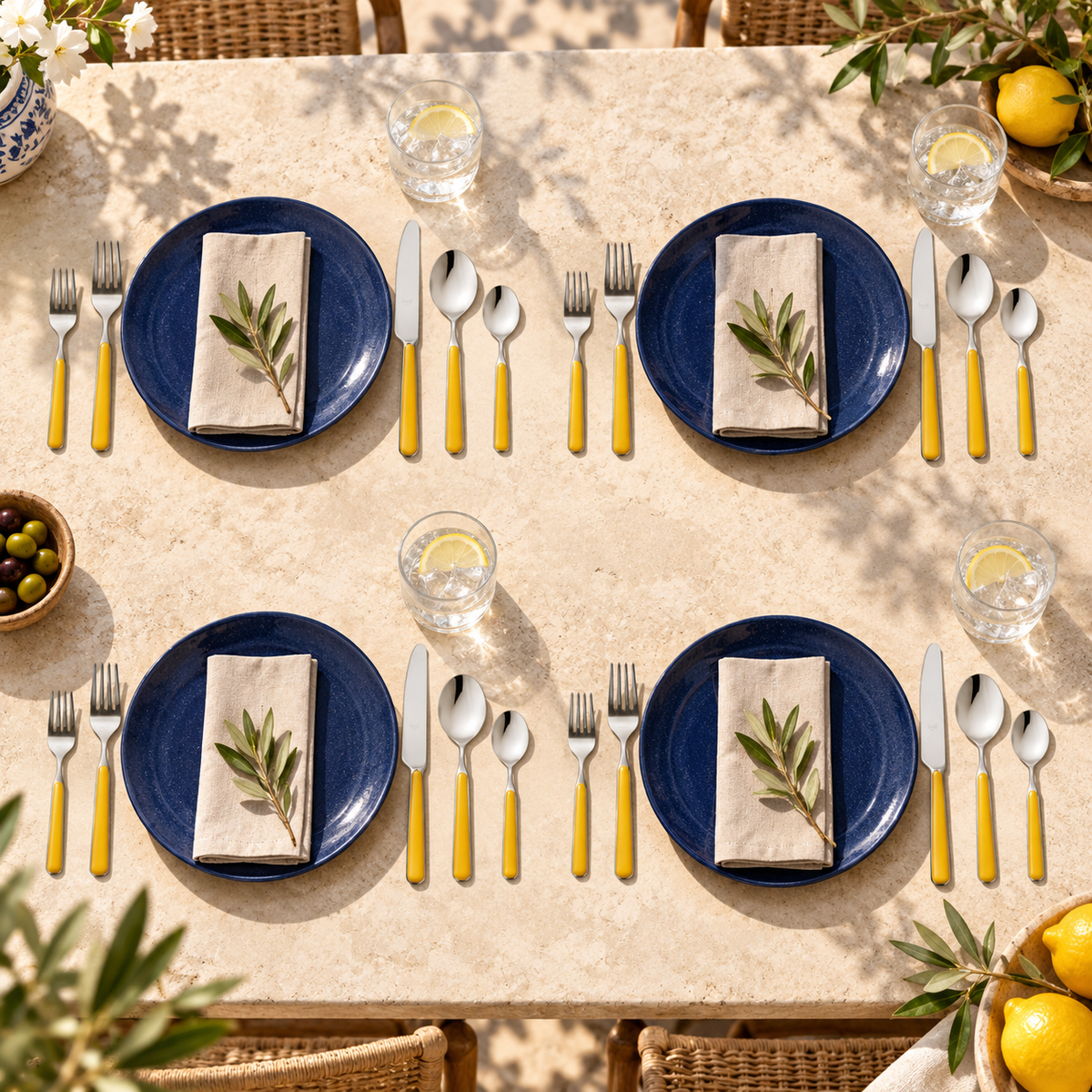 Mepra Fantasia Ice Oro Mustard 20-piece flatware arranged as four sunlit Mediterranean place settings