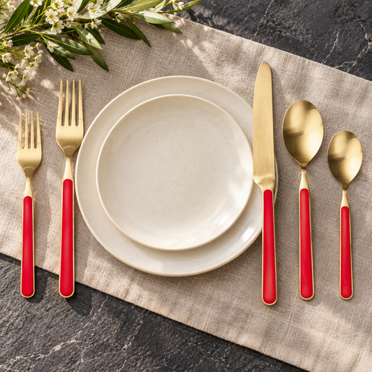 Mepra Fantasia Ice Oro Red five-piece place setting on ivory linen, with brushed gold metal and red handles