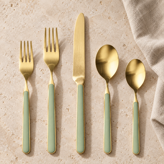Mepra Fantasia Ice Oro Sage five-piece flatware on pale stone, brushed gold with muted sage handles