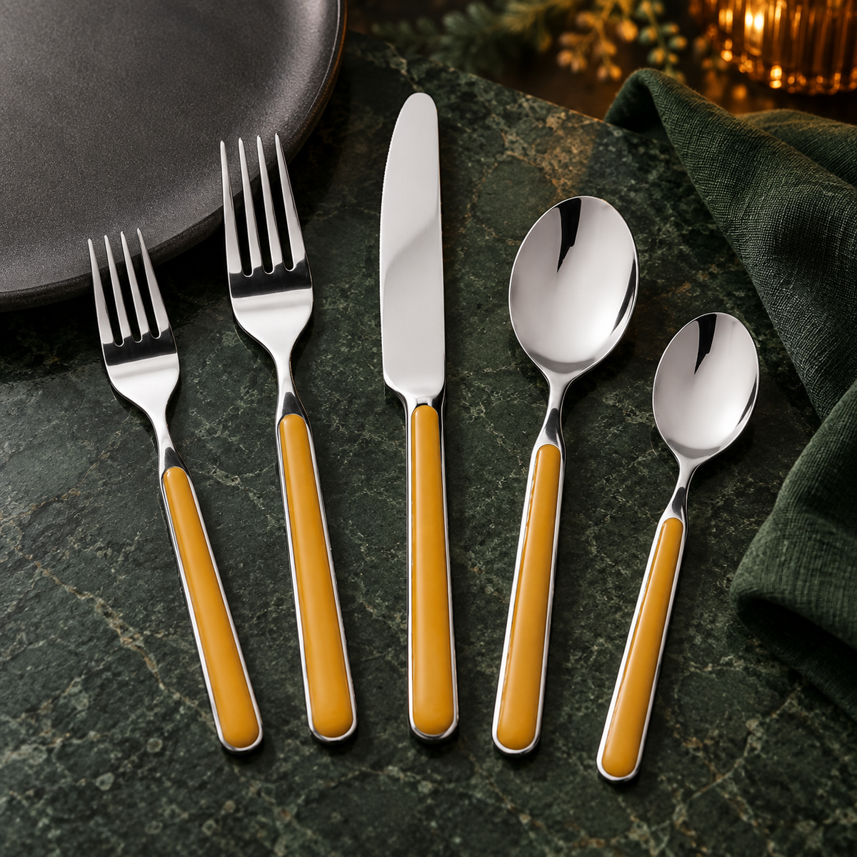Mepra Fantasia Mustard five-piece flatware on forest green stone