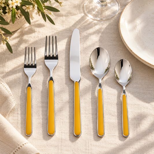 Mepra Fantasia Mustard five-piece flatware on ivory linen beside a ceramic plate