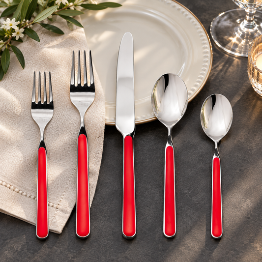 Mepra Fantasia Red five-piece flatware beside ivory dinnerware on dark stone
