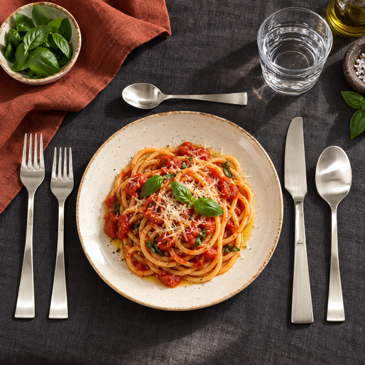 Mepra Italia Ice five-piece flatware setting with pasta on charcoal linen