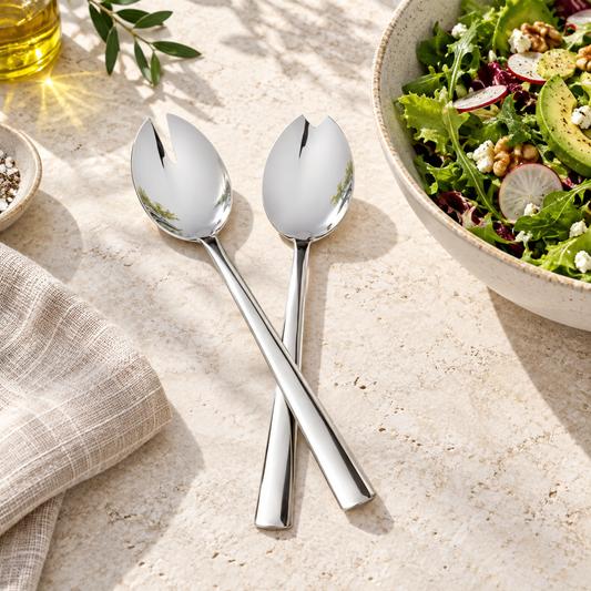 Two Mepra Levantina salad servers beside a salad bowl on light stone