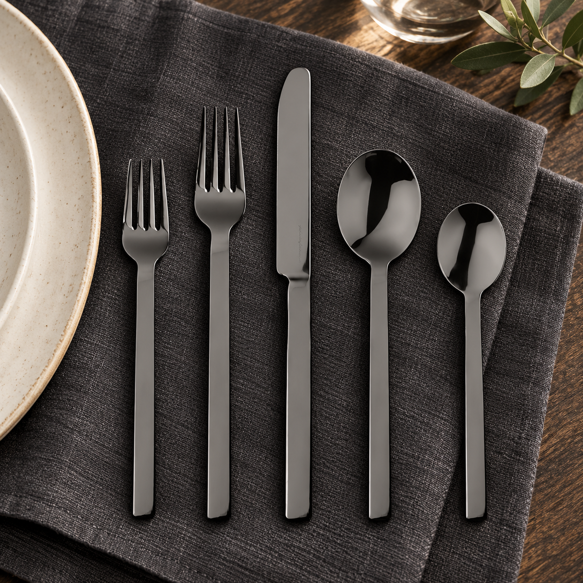 Representative five-piece setting from Mepra Stile Oro Nero 20-piece set on charcoal linen