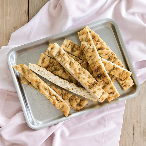 Breadsticks on a metal tray with a pink cloth background