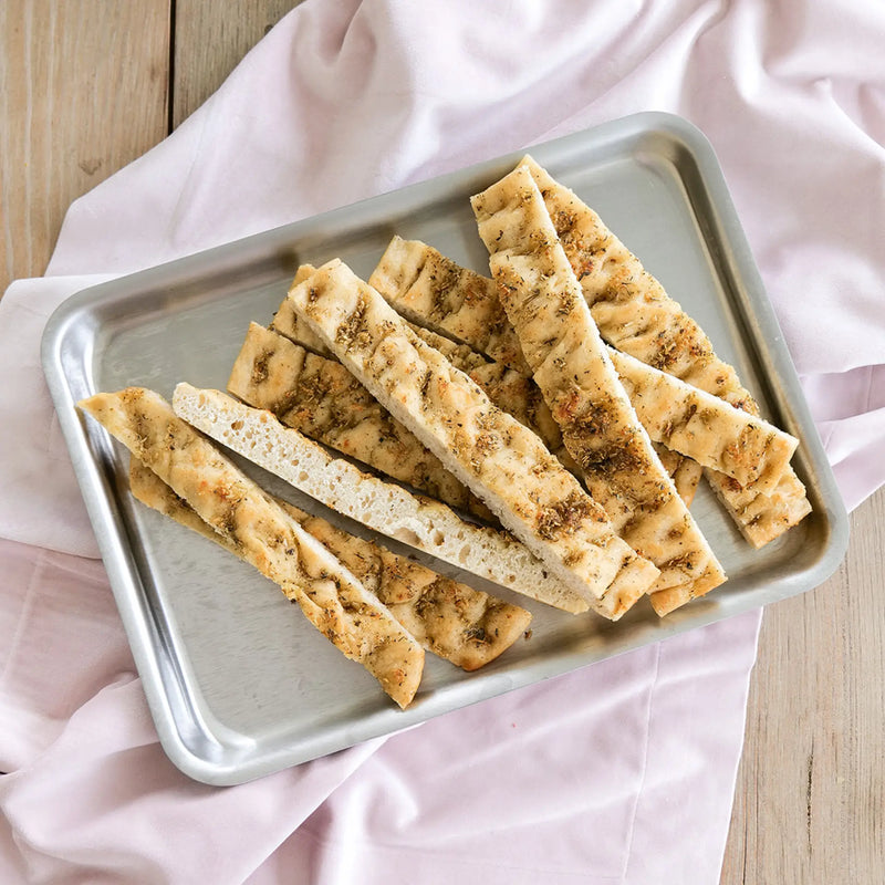 Breadsticks on a metal tray with a pink cloth background